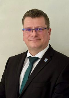 Nagy Zoltán, Celldömölk alpolgármesterének portréja. Sötét zakót, fehér inget és zöld nyakkendőt visel, zakójának hajtókáján Celldömölk város címeres kitűzője látható.